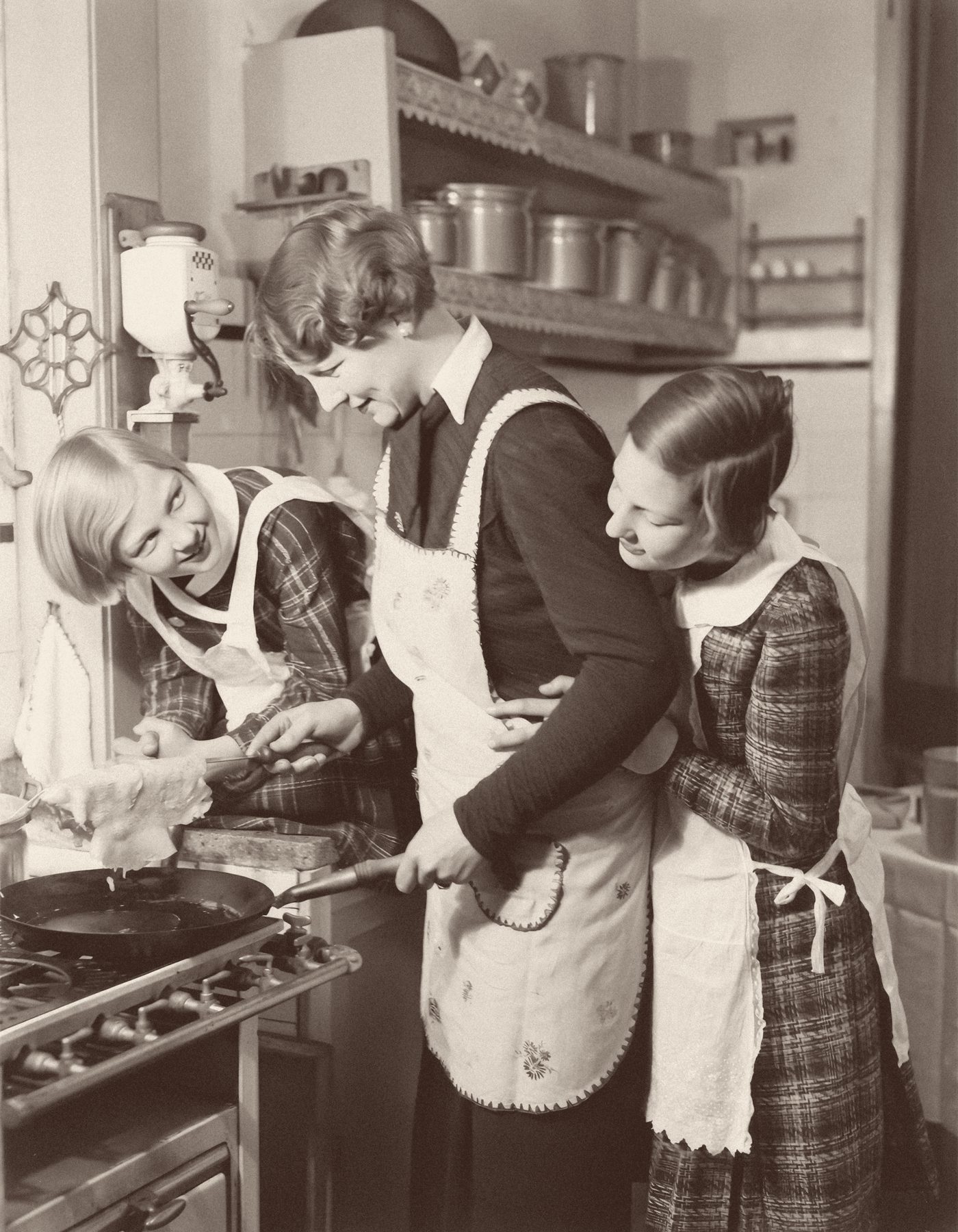 A vintage photograph of a mother and two daughters cooking together